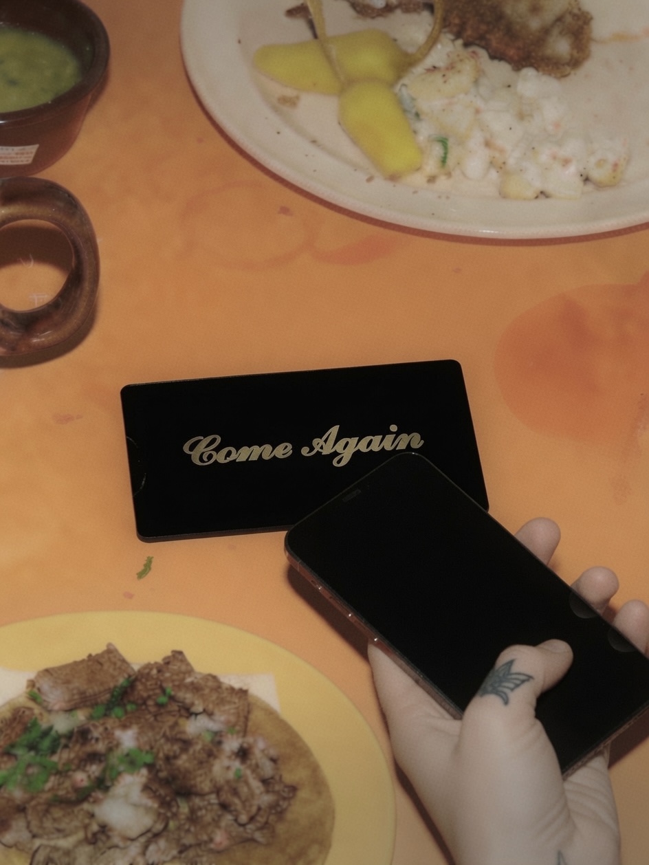A hand taps a phone against an IRLs card beside a taco